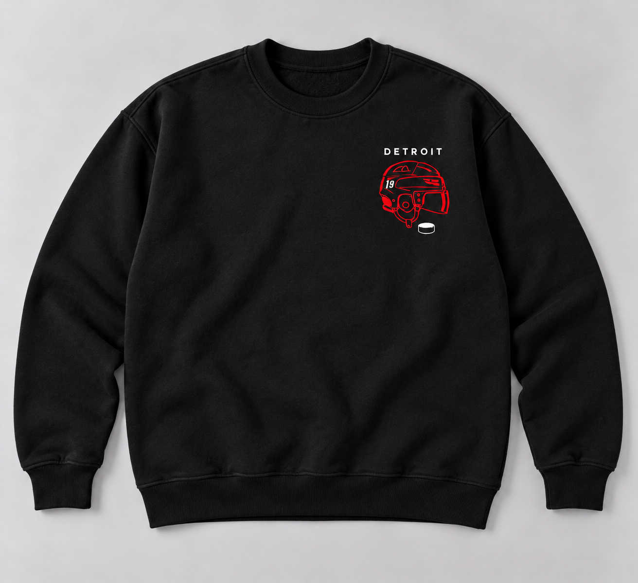 Black crewneck sweatshirt with small white Detroit lettering, a red hockey helmet with a subtle white 19, and a white puck on the left chest